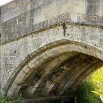 Wiveton Bridge showing stone ribbing underneath arch. From garden of Stonebridge house, 2023